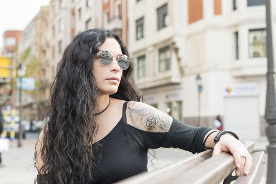 Fashion Heavy Metal Style Woman Sitting On Wood Bench In The Street.