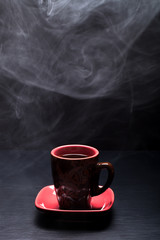 A cup of coffee with smoke on black background