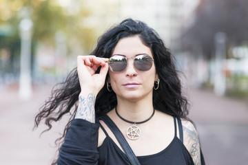 Urban portrait of woman with tattoo and sunglasses heavy metal style.