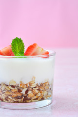 Yogurt with cereals, strawberries and pink background