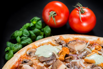 closeup Tasty pizza with mushrooms, ham and pickles on a black b