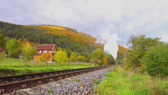 Old Steam Locomotive Moves on Rails Between the Hills