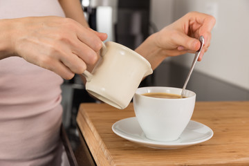 Woman adding milk to her coffee