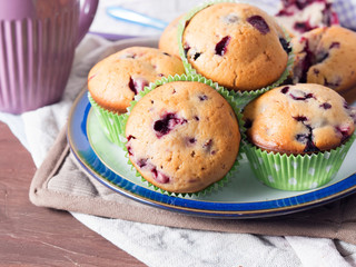 Home made muffins with blackberries and blueberries on brown wooden table with table napkins, closeup