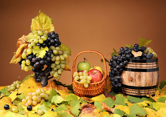 Grapes in a wicker basket and apples on a table