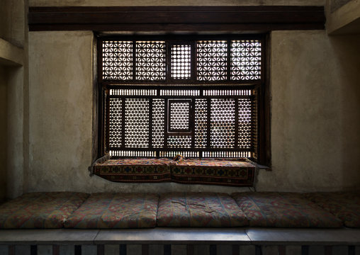 Aged interleaved wooden window (Mashrabiya) and a built-in couch