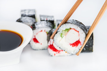 close up of chopsticks taking portion of sushi roll on the table