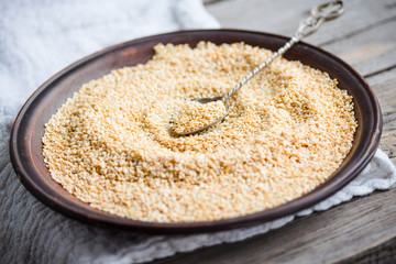 sesame seeds in a clay dish, a teaspoon of seeds