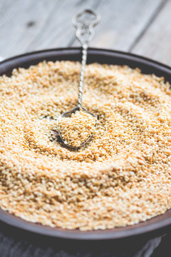 sesame seeds in a clay dish, a teaspoon of seeds