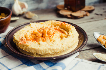 Appetizer hummus with tahini paste, olive oil, paprika in rustic