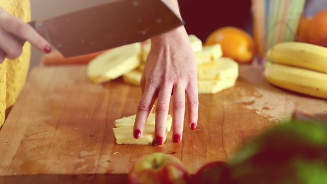 View of woman hands cutting pineapple into pieces