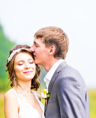 Young wedding couple enjoying romantic moments outside on a summer meadow.