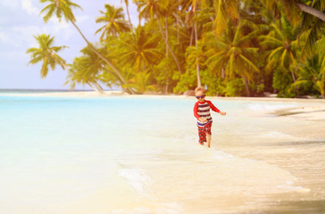 little boy running splashing water on beach