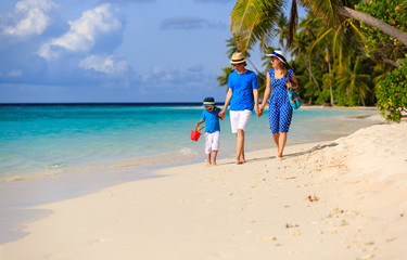 family with child walking on tropical beach