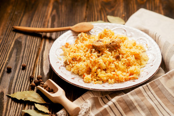 
national cuisine , stewed rice with meat , which is called pilaf with bay leaf and pepper on a wooden background 