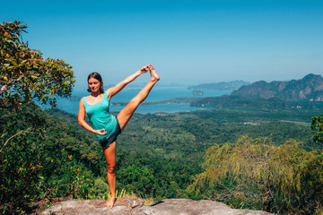 Girl on the view poinf of the mountain, doing yoga asana, Tab Kak Hang Nak Nature Trail, Thailand