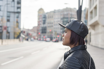 Profile portrait of young woman with baseball cap in the street.