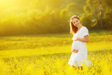 Fototapeta premium beautiful pregnant woman in summer nature meadow with yellow flo
