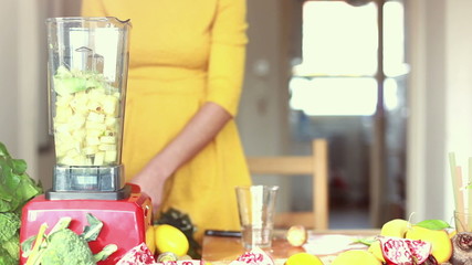 Woman pouring water in blender with pineapple and avocado - Powered by Adobe