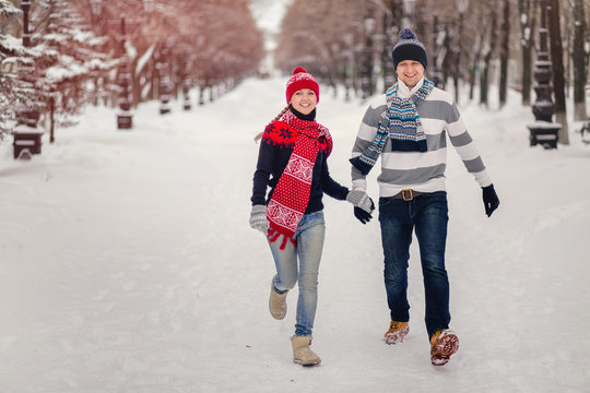 Happy, Young Couple Runing In Snowy Winter Park.