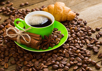 Close-up of coffee cup with roasted coffee beans on wooden backg