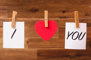 Red Valentine's heart and words I love you hanging on line on wooden background