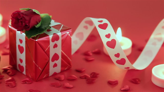 Chocolate cupcake against a red background with roses and gift at candlelight for a bright, fun and cheerful Valentines Day. Love and romance concept.