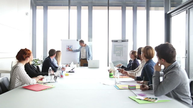 Handsome creative director giving presentation, pointing at flipchart