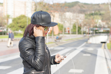 Fashion woman listening music in the street.