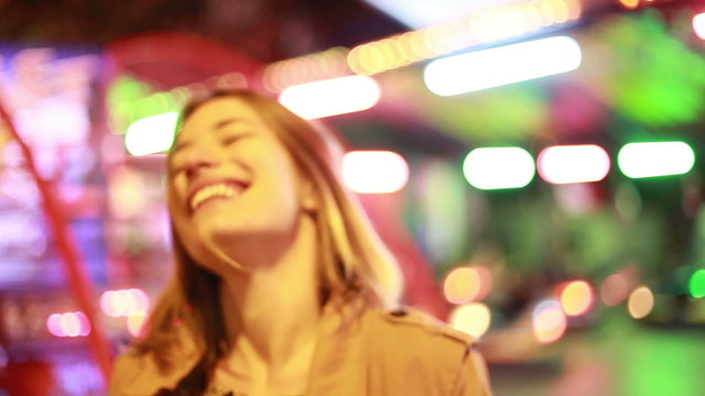 Portrait of woman looking at camera and laughing in amusement park