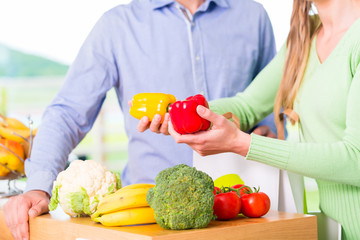Couple unpacking grocery shopping bag at home