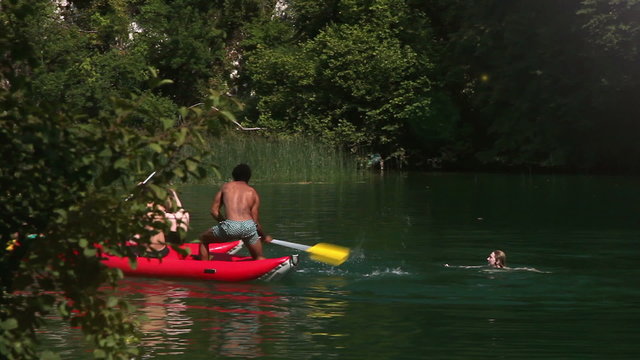 Two male friends riding canoe and splashing their female friends with paddles