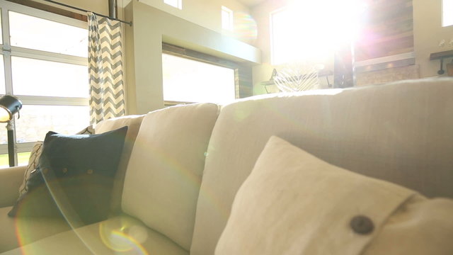 From Living Room to Reveal Kitchen Sun Flare. camera rises from the couch to reveal a modern kitchen. Sun flare hits in the camera through large windows. Industrial new design
