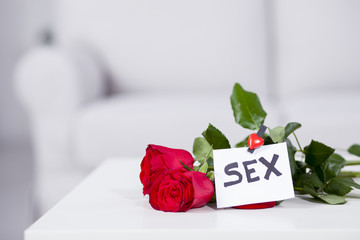 Red roses on the table with note Sex