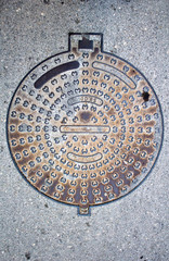 Manhole cover on the grey asphalt