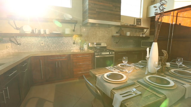 Modern Kitchen Dolly Left from Sun Flare Through Window. camera moves left on a modern kitchen. Sun flare coming through large windows showing all details of the kitchen and move to sink
