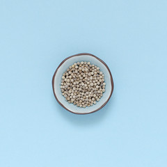 single spice bowl with white pepper on turquoise background