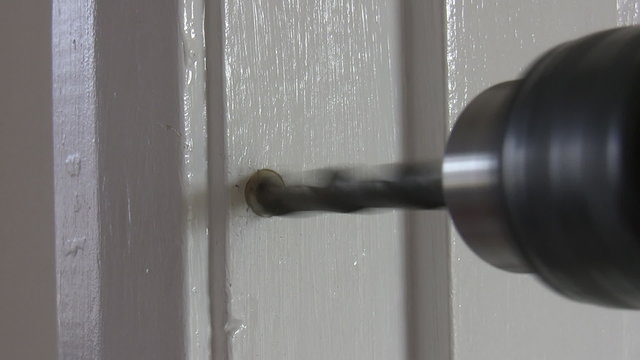 Close up of electric drill drilling a hole in the wooden door frame