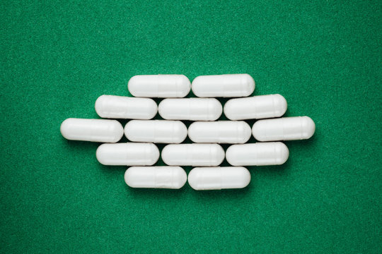 white capsules pills on green background