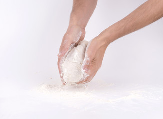 Kneading dough; close-up of male hands in flour kneading dough
