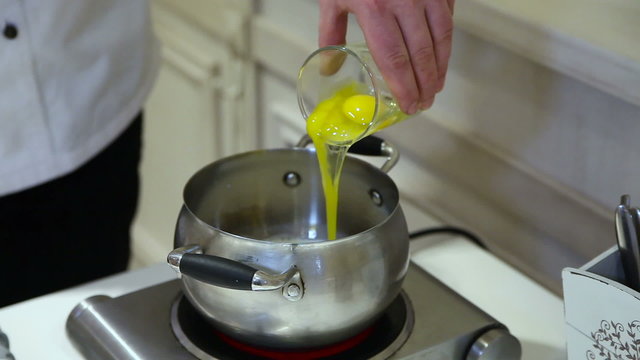 The cook pours a glass of egg into the pan. Prepare meringue dessert. Close-up