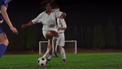 A female soccer player dribbles down the field during a game at night - Powered by Adobe