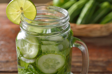 Detox water with lime and cucumbers in a mason jar against a rus