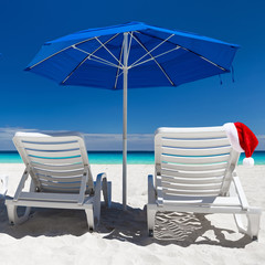 Caribbean beach with blue sun umbrellas and white sunbeds