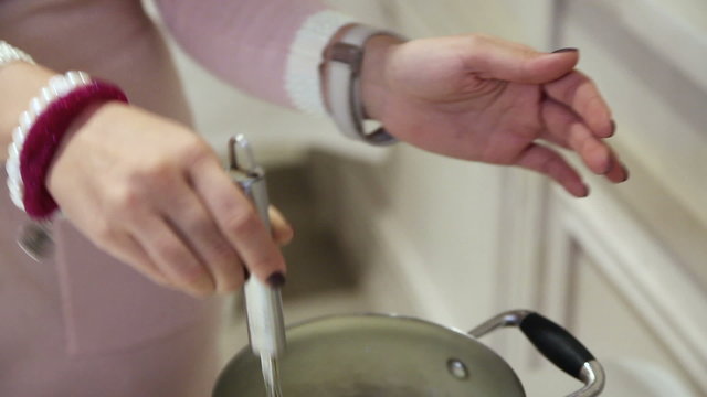She boils cream meringue in a pan. Close-up