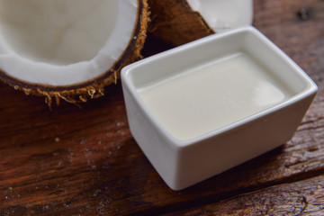Coconut and coconut milk in square white bowl on wooden table