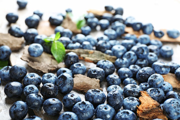 Tasty ripe blueberries with green leaves on wooden table close up