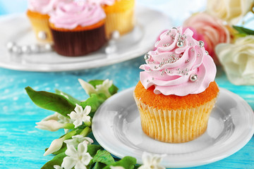 Tasty cupcakes on plate, on color wooden background