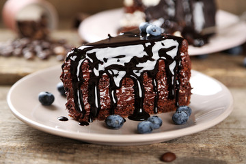 Chocolate cake with chocolate cream and fresh blueberries on plate, on wooden background