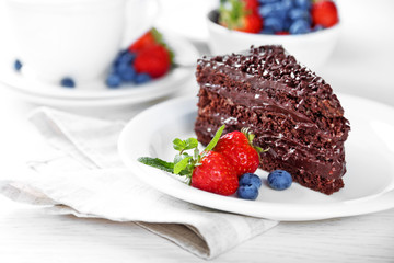 Chocolate cake with chocolate cream and fresh berries on plate, on light background
